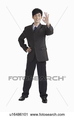 Young man standing with arms akimbo and making Ok sign with smile View Large Photo Image Stock Image - Young man standing with arms akimbo and making Ok sign with smile. Fotosearch