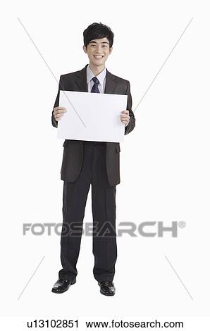 Stock Image - Young man standing with smile and holding a paper. Fotosearch