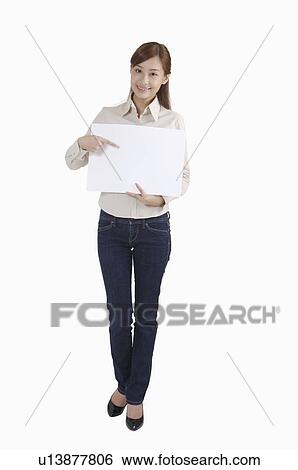 Stock Photograph - Young woman holding and pointing a paper with smile. Fotosearch
