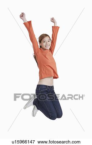 Young woman jumping in mid-air with arms outstretched and smiling View Large Photo Image Stock Photo - Young woman jumping in mid-air with arms outstretched and smiling. Fotosearch