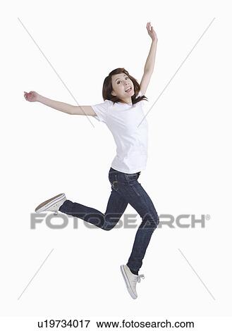 Stock Photo - Young woman jumping with arms outstretched and smiling. Fotosearch