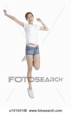 Stock Photograph - Young woman jumping with arms outstretched and mouth open. Fotosearch