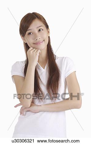 Stock Image - Young woman looking away with hand on chin and smiling. Fotosearch