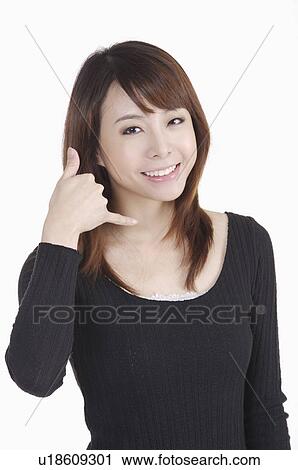 Stock Image - Young woman making call me gesture and smiling. Fotosearch