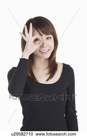 Young woman making OK sign on eye and smiling View Large Photo Image Stock Image - Young woman making OK sign on eye and smiling. Fotosearch