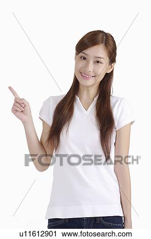 Young woman pointing away and smiling happily View Large Photo Image Stock Image - Young woman pointing away and smiling happily. Fotosearch