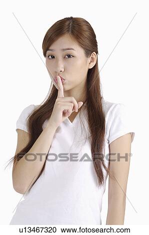 Young woman puckering and putting finger on lips View Large Photo Image Stock Image - Young woman puckering and putting finger on lips. Fotosearch