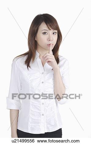 Young woman putting finger on lips and looking at the camera View Large Photo Image Stock Photograph - Young woman putting finger on lips and looking at the camera. Fotosearch