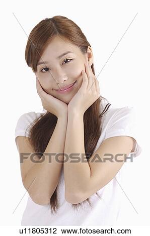 Young woman smiling with hands on chin and looking at the camera View Large Photo Image Stock Image - Young woman smiling with hands on chin and looking at the camera. Fotosearch