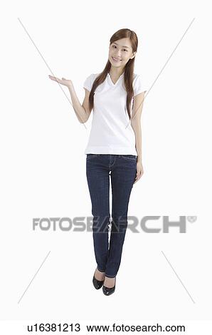 Stock Image - Young woman standing and pointing with smile. Fotosearch