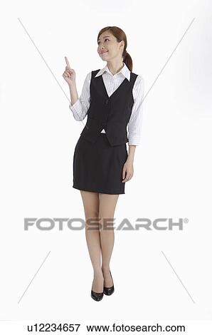 Young woman standing, pointing and looking up with smile View Large Photo Image Stock Photo - Young woman standing, pointing and looking up with smile. Fotosearch
