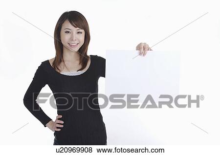 Young woman standing with arms akimbo and holding a paper with smile View Large Photo Image Stock Photo - Young woman standing with arms akimbo and holding a paper with smile. Fotosearch
