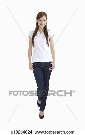 Young woman standing with hands in pockets and smiling View Large Photo Image Picture - Young woman standing with hands in pockets and smiling. Fotosearch