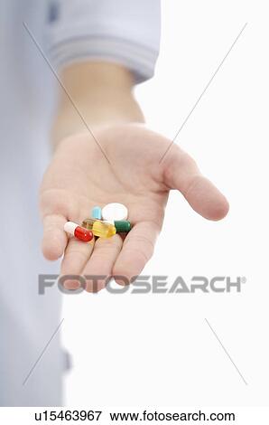 Stock Photo - Close-up of human hand holding pills. Fotosearch