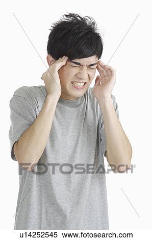Stock Photography - Young man frowning and putting hands on head of illness. Fotosearch