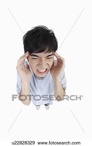 Stock Photo - Young man having headache for anxiety. Fotosearch