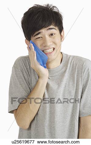Young man having toothache and holding ice pack on cheek View Large Photo Image Stock Photo - Young man having toothache and holding ice pack on cheek. Fotosearch