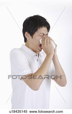Stock Photography - Young man rubbing nose with toilet paper. Fotosearch