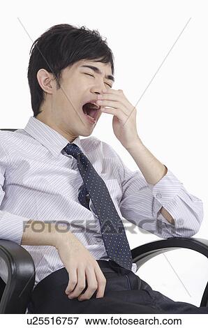 Stock Photo - Young man sitting and yawning with eyes closed. Fotosearch