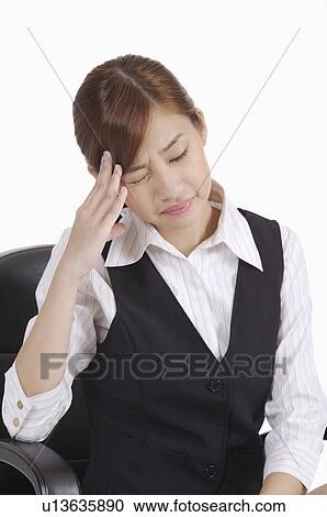 Stock Image - Young office lady sitting and having headache. Fotosearch