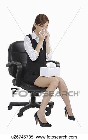 Stock Photography - Young office lady sitting on chair and running nose. Fotosearch