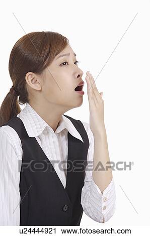 Stock Image - Young office lady yawning of exhaustion and looking away. Fotosearch