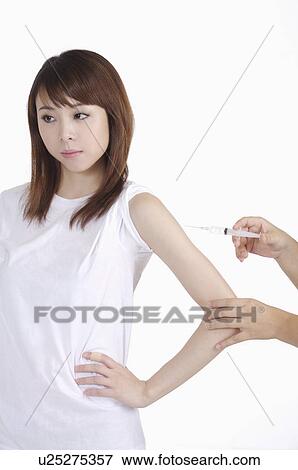 Stock Photo - Young woman having injecting and standing with arms akimbo. Fotosearch