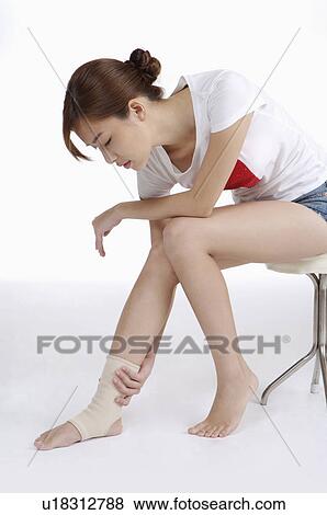 Stock Photo - Young woman having physical injury on ankle. Fotosearch