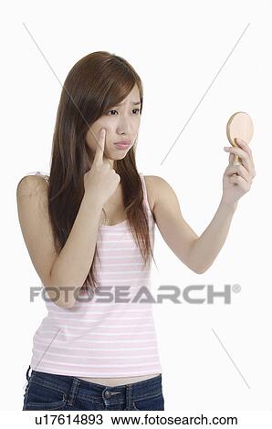 Young woman holding mirror and frowning for acne View Large Photo Image Stock Image - Young woman holding mirror and frowning for acne. Fotosearch