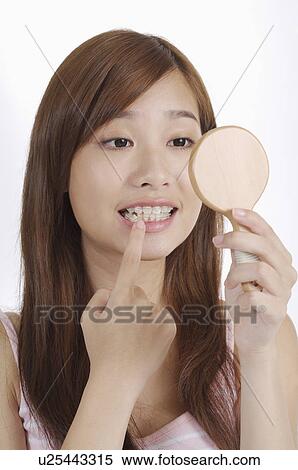 Young woman looking into mirror for dental hygiene View Large Photo Image Stock Photography - Young woman looking into mirror for dental hygiene. Fotosearch
