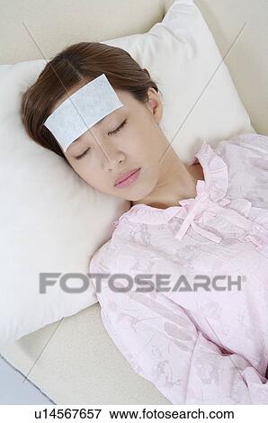 Stock Photo - Young woman lying on bed for headache. Fotosearch