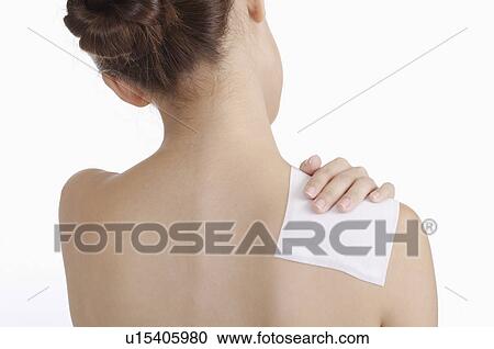 Stock Image - Young woman sticking medicine on shoulder of pain. Fotosearch