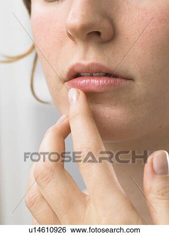 Stock Photograph - Woman is touching her lip. Fotosearch