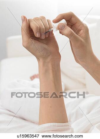 Stock Photo - Woman is varnishing her nails. Fotosearch