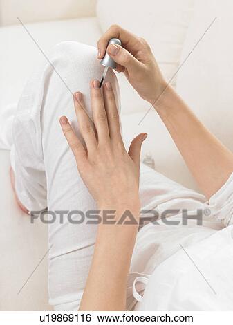 Stock Photograph - Woman is varnishing her nails. Fotosearch