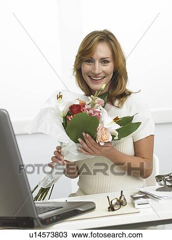 Woman with a bouquet sitting on her desk View Large Photo Image Stock Image - Woman with a bouquet sitting on her desk. Fotosearch