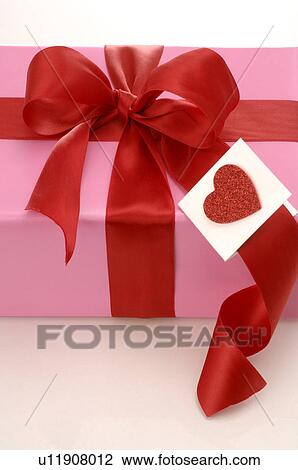 Stock Image - Gift with a red ribbon and a red heart. Fotosearch