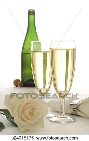 Stock Photography - Two glasses of sparkling wine and a white rose blossom. Fotosearch