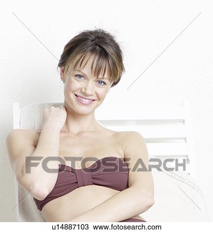 Stock Image - Woman in bikini lying on deck chair. Fotosearch