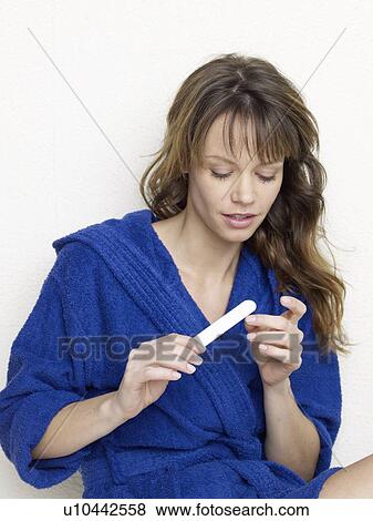 Stock Photo - Woman in blue bathrobe filing nails. Fotosearch