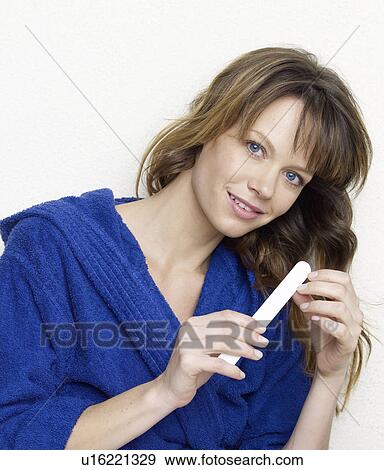 Stock Photo - Woman in blue bathrobe filing nails. Fotosearch