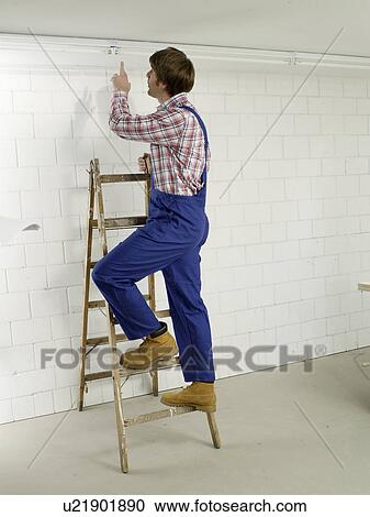 Man in work wear on a ladder View Large Photo Image Stock Image - Man in work wear on a ladder. Fotosearch