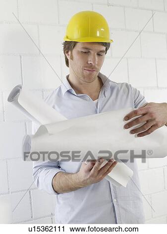 Stock Image - Man is reading construction plans. Fotosearch