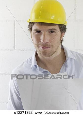 Man wearing a helmet is holding some sheets of paper View Large Photo Image Stock Image - Man wearing a helmet is holding some sheets of paper. Fotosearch