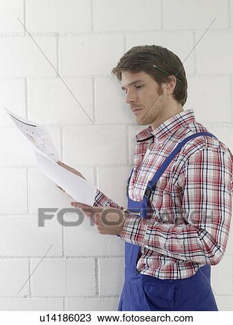 Man wearing work wear is holding construction plans View Large Photo Image Stock Image - Man wearing work wear is holding construction plans. Fotosearch