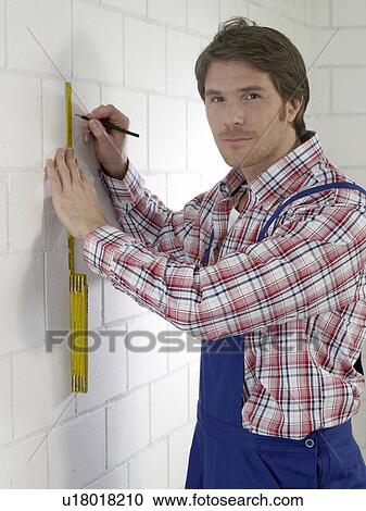 Stock Image - Man wearing work wear with pencil and folding rule. Fotosearch