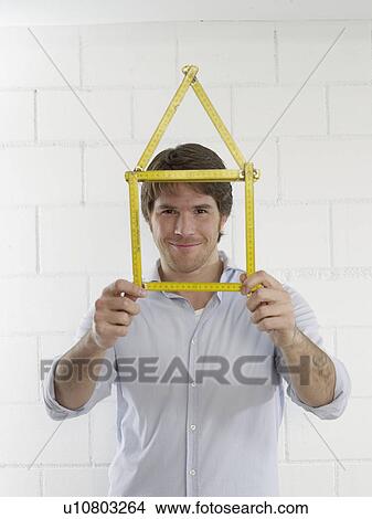 Picture - Man with a folding rule looking like a house. Fotosearch