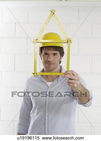 Stock Photography - Man with a folding rule looking like a house. Fotosearch