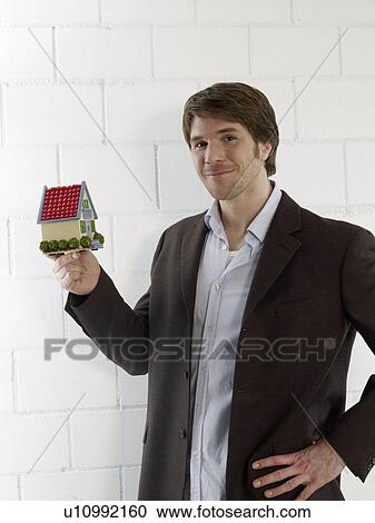 Stock Image - Mann holding a small model house. Fotosearch
