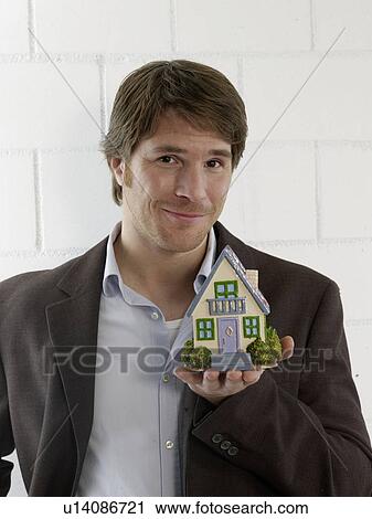 Stock Image - Mann holding a small model house. Fotosearch